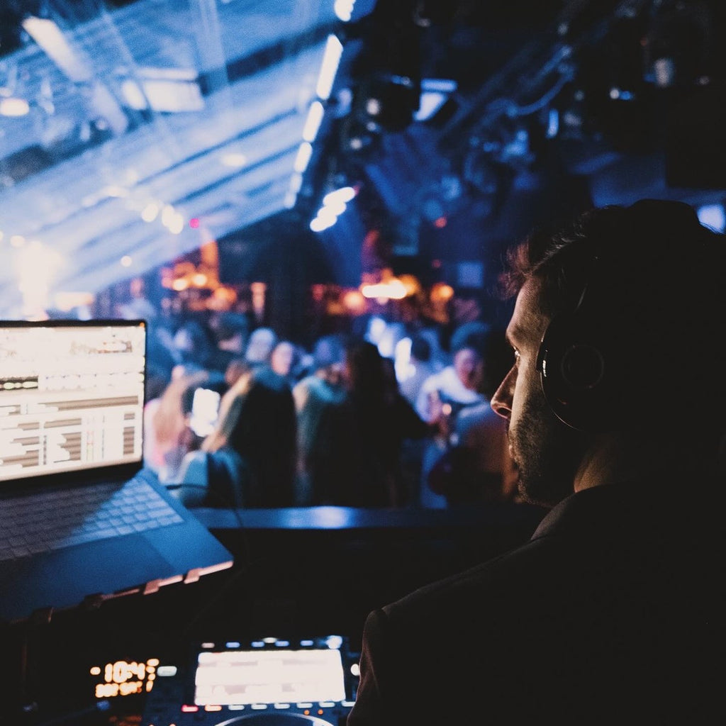 DJ Nugget spinning at a nightclub with lasers and a packed crowd