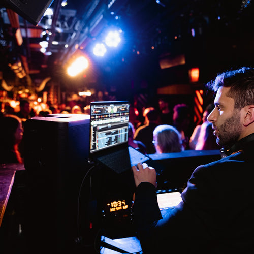 DJ Nugget in a nightclub with warm stage lighting and a packed crowd